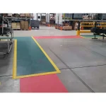 Zelena i crvena ergonomska podloga sa žutim ivicama u magacinskom prolazu