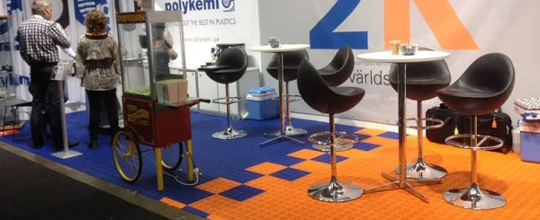 Sajamski štand sa barskim stolicama na plavo-narandžastoj modularnoj podlozi