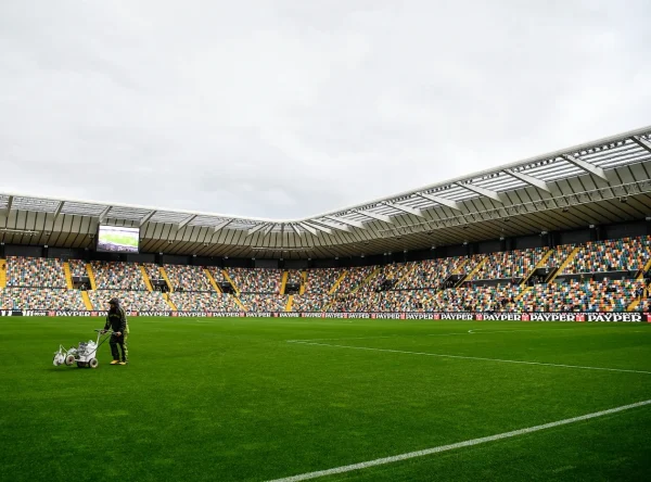Postavljanje veštačke trave na stadionu sa tribinama u pozadini
