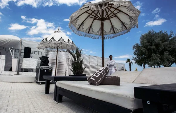Ležaljka sa suncobranom na beloj podlozi terase uz plažu