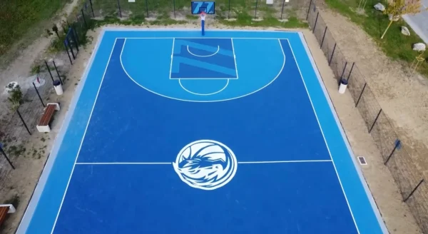 Plavi košarkaški teren sa velikim klupskim znakom na sredini igrališta