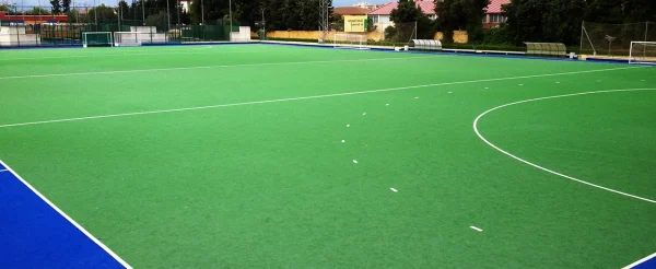 Zeleni teren od veštačke trave sa plavom obodnom zonom i belom linijom